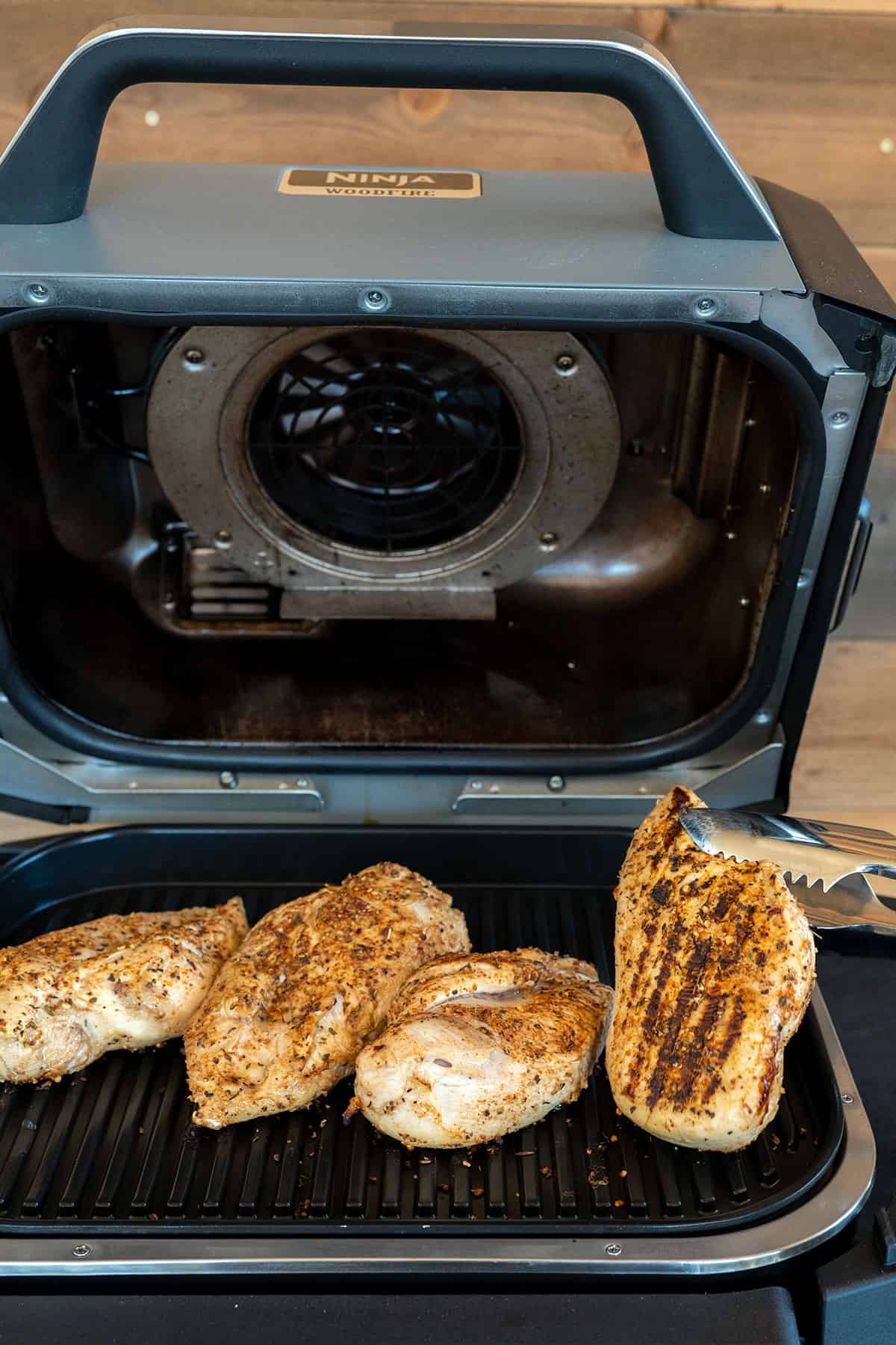 Flipping chicken breasts on the grill.
