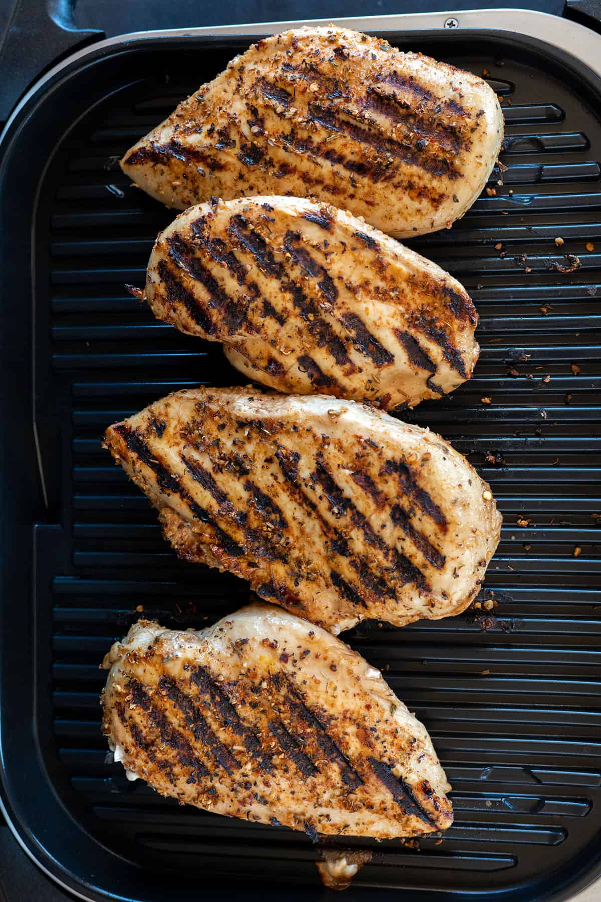 four chicken breasts with grill marks on Ninja Grill.