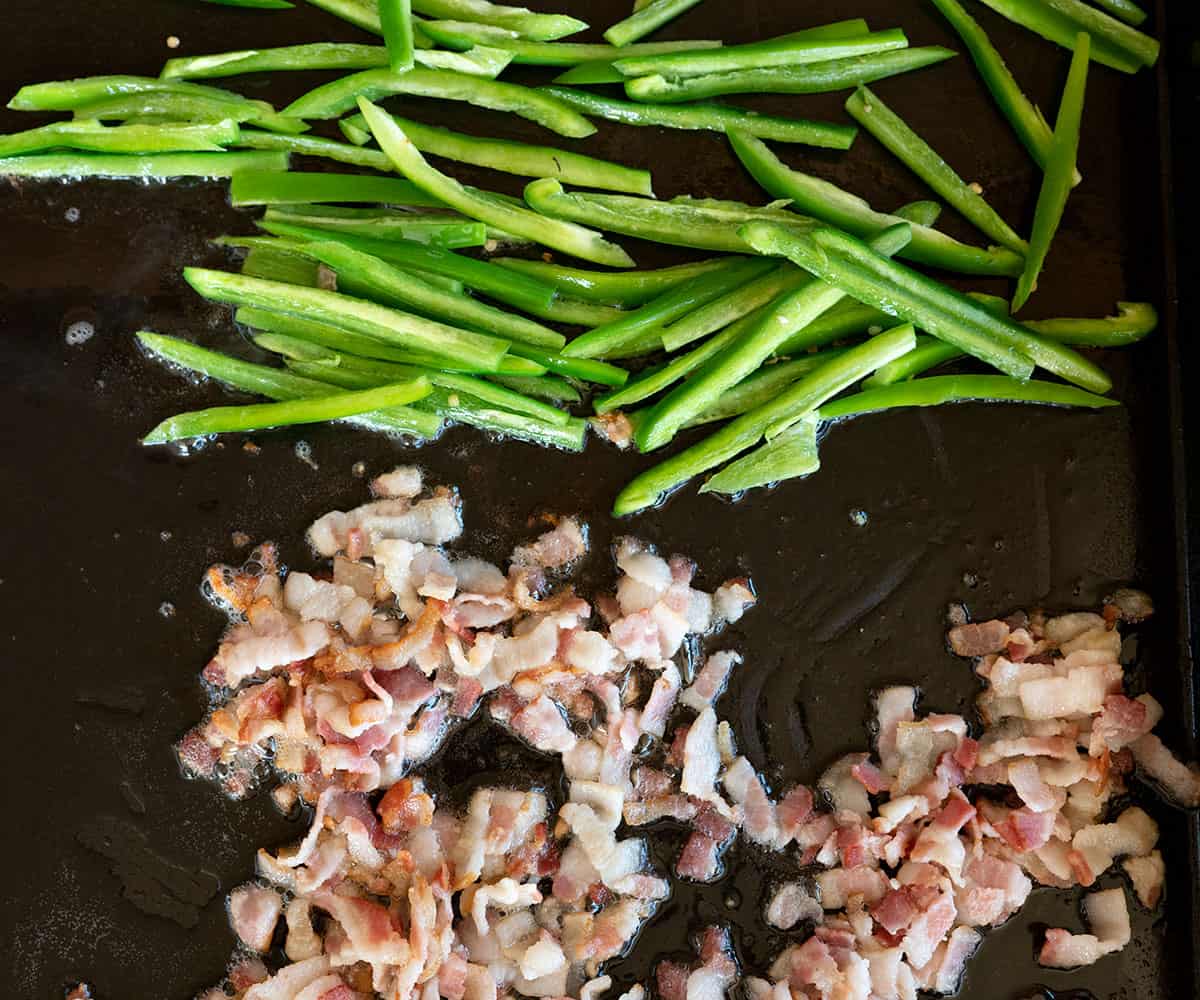 diced bacon and jalapeno strips cooking on griddle.