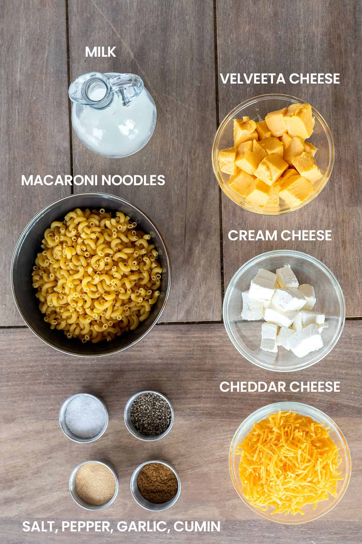 Smoked Mac and Cheese ingredients: milk, macaroni noodles, velveeta cheese, cream cheese, cheddar cheese, salt, pepper, garlic, cumin.