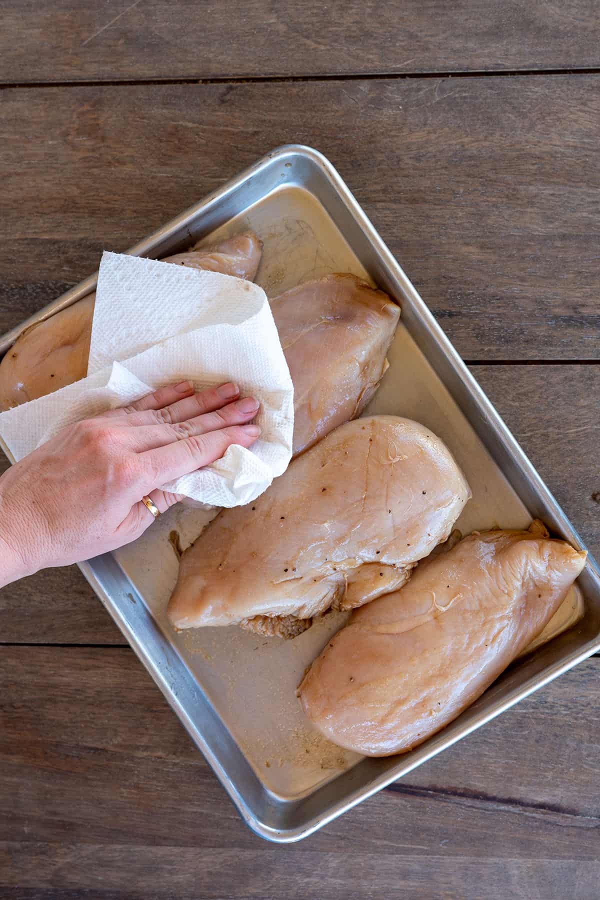 patting four chicken breasts dry with a paper towel.