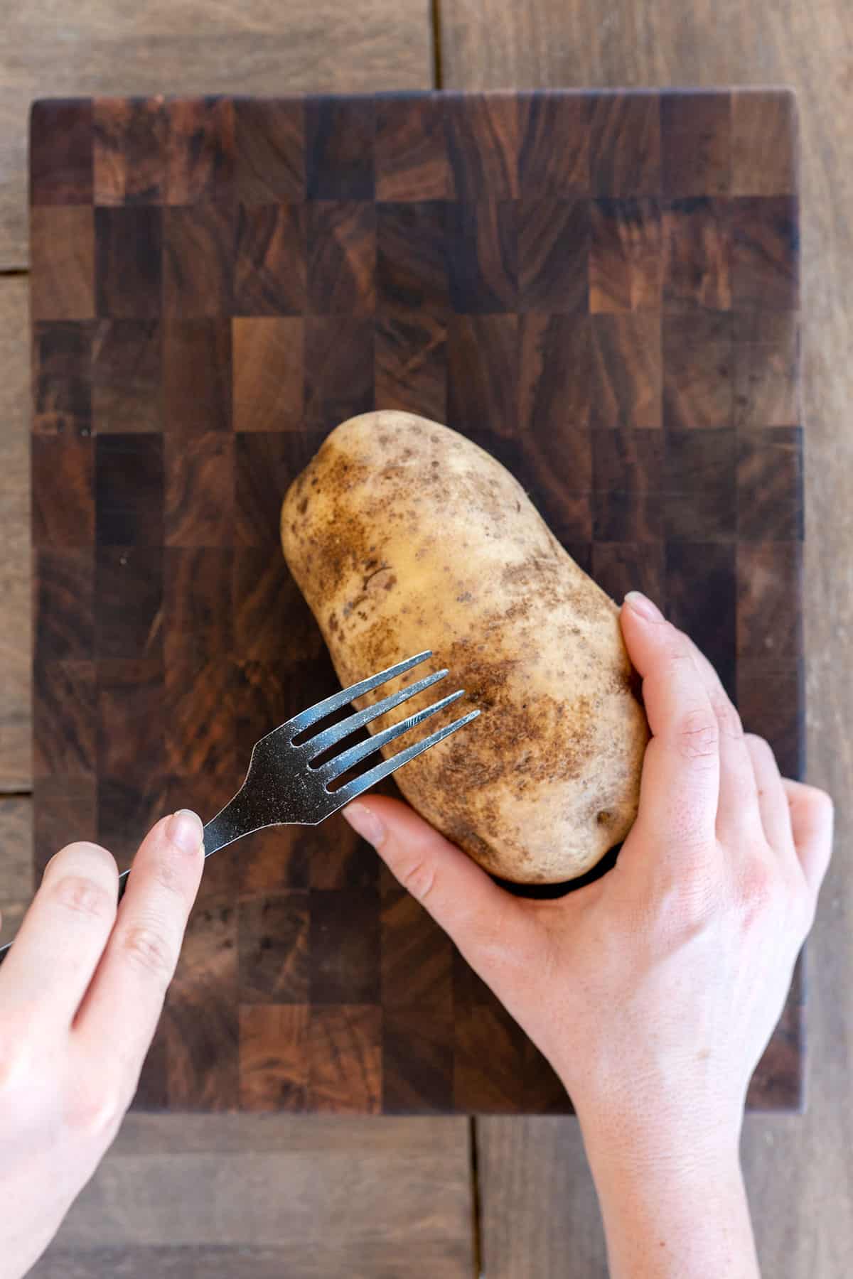 piercing a raw potato with a fork.