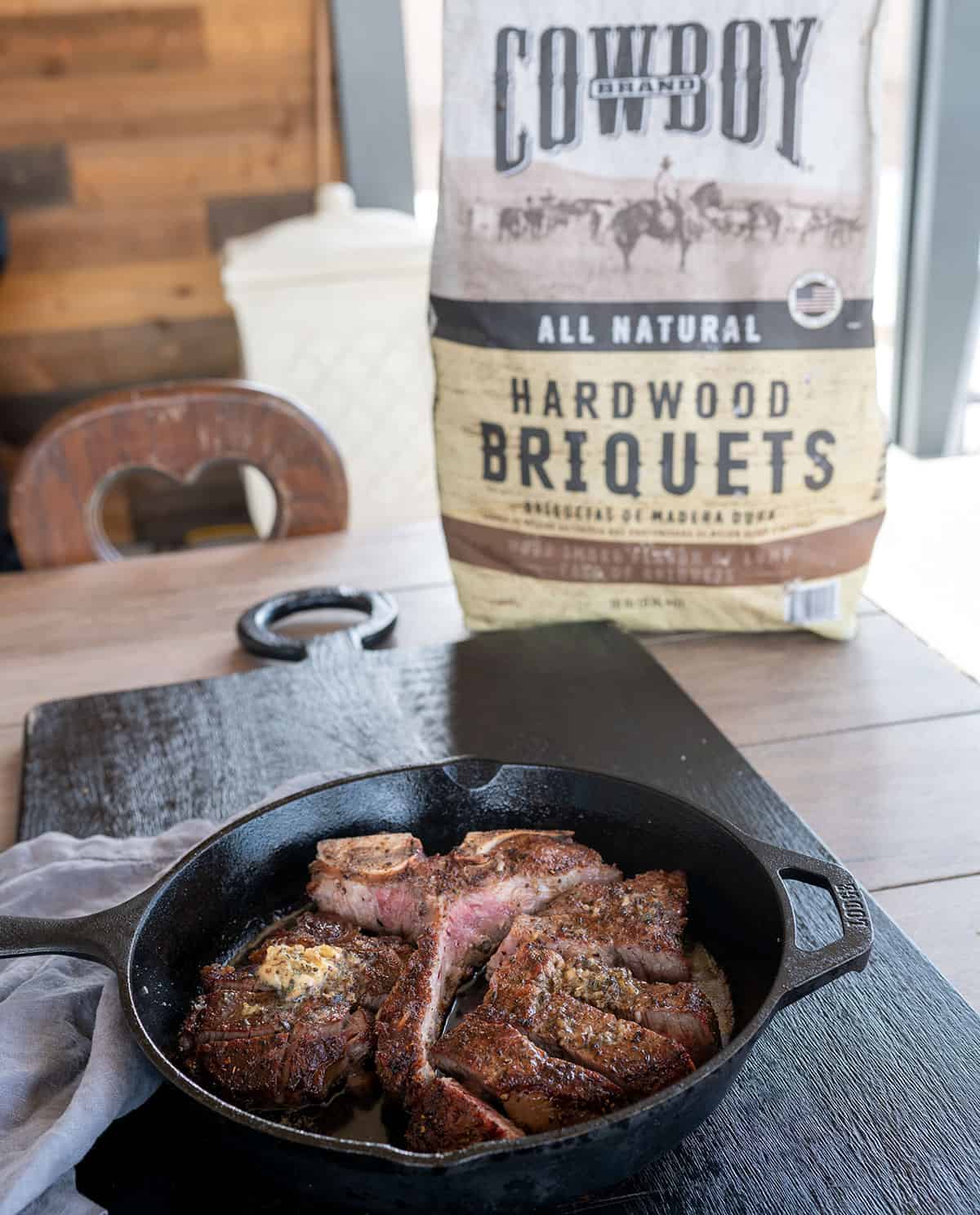 bag of Cowboy Charcoal on table by skillet of grilled porterhouse steak.