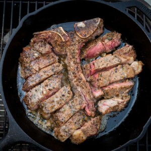 sliced porterhouse steak in skillet with melted compound butter.