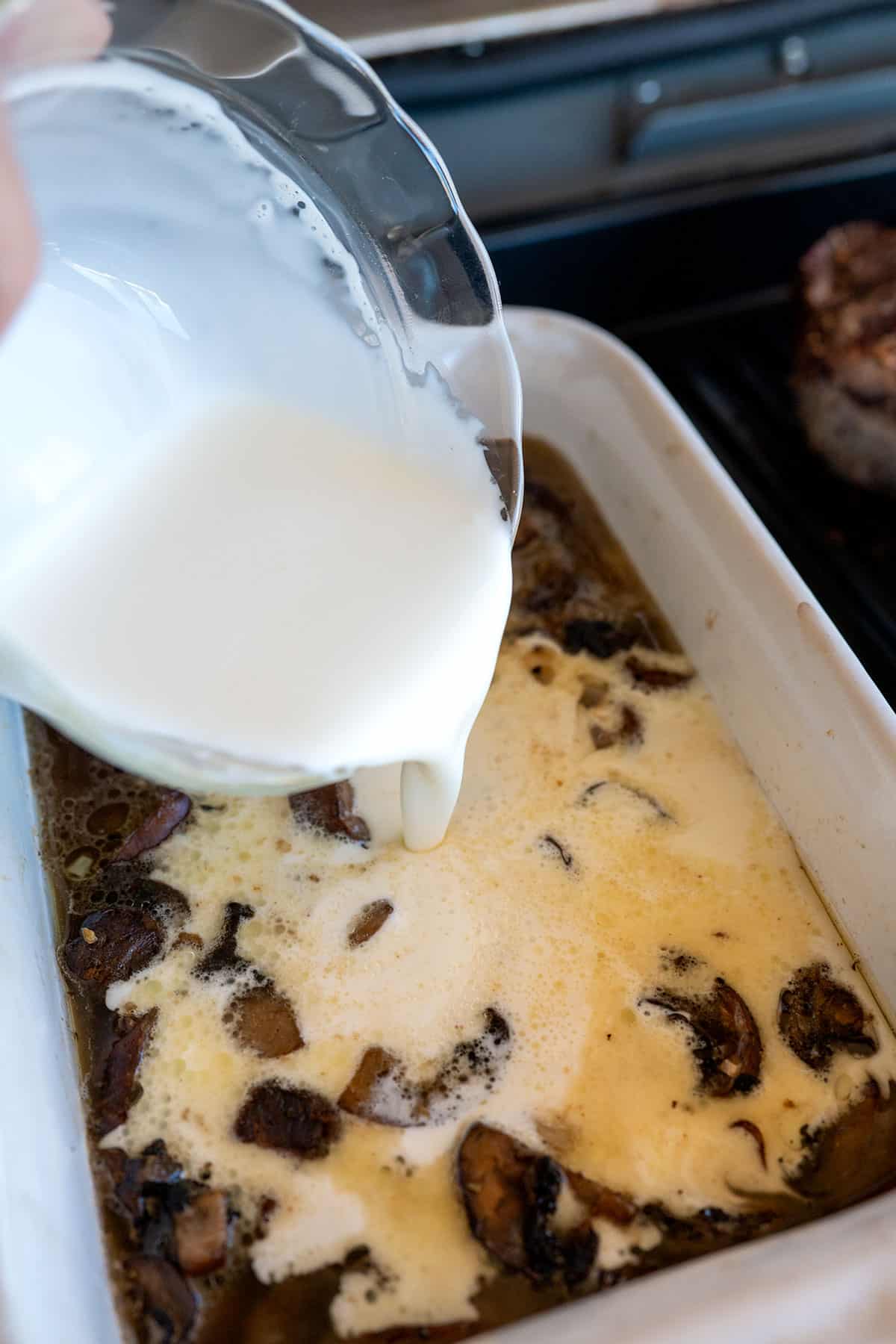 pouring cream into baking dish with mushrooms.