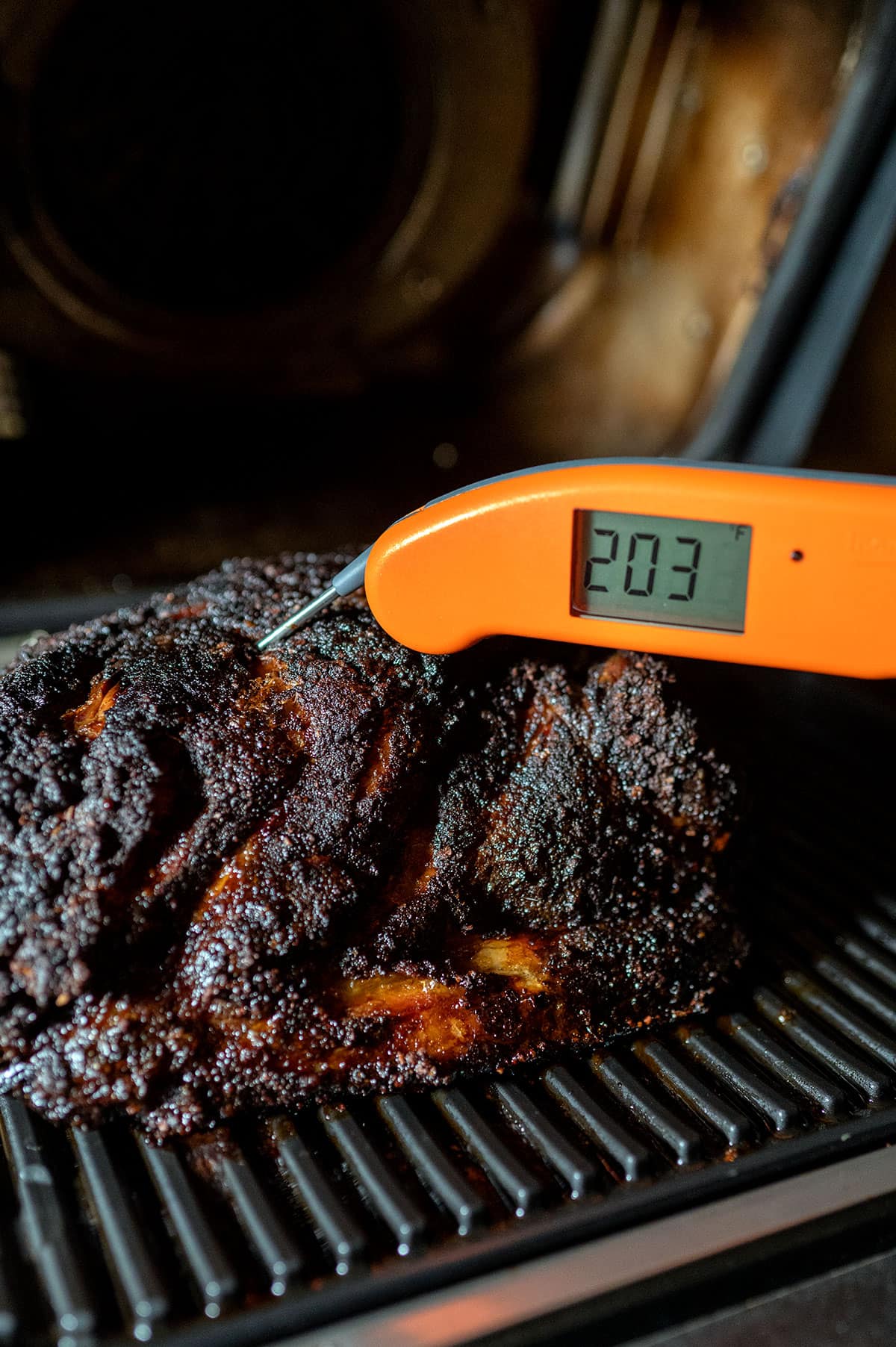 pork shoulder on grill registering a 203-degree internal temperature.