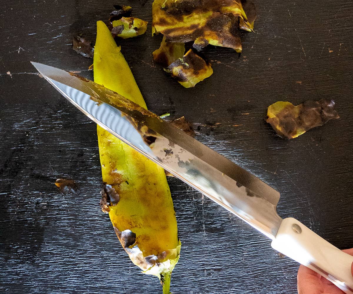 using a knife to remove skin from hatch chile pepper.