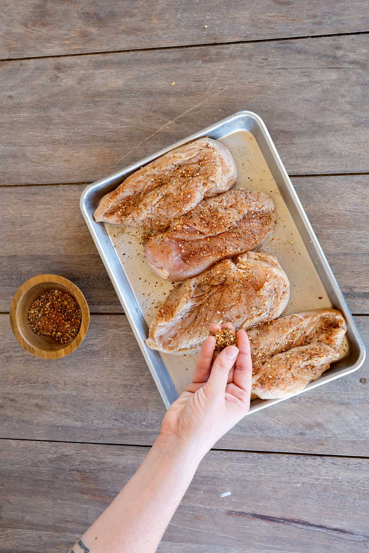 adding seasoning to four chicken breasts.