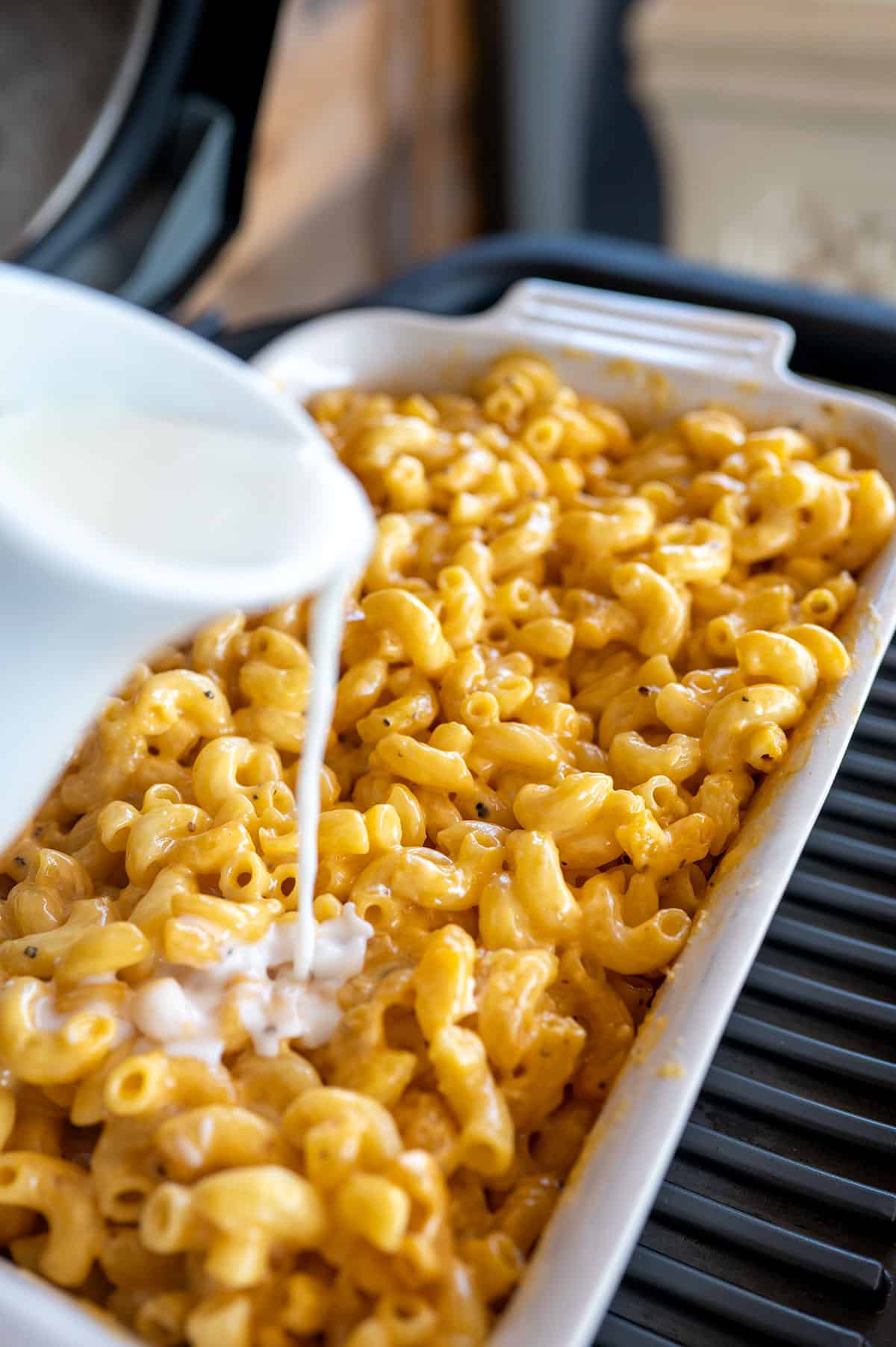 pouring milk into dish with Smoked Mac and Cheese.