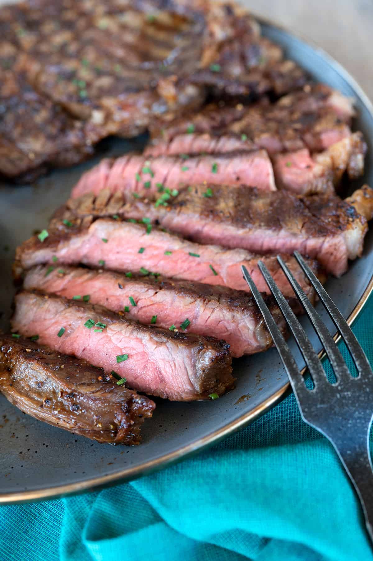 sliced medium rare ribeye steaks on gray plate.