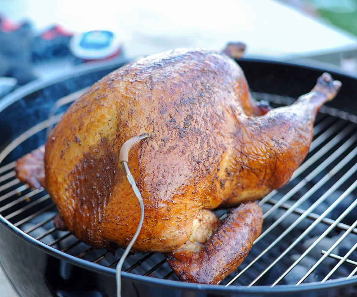 smoked turkey sitting on weber grill with igrill thermometer in breast