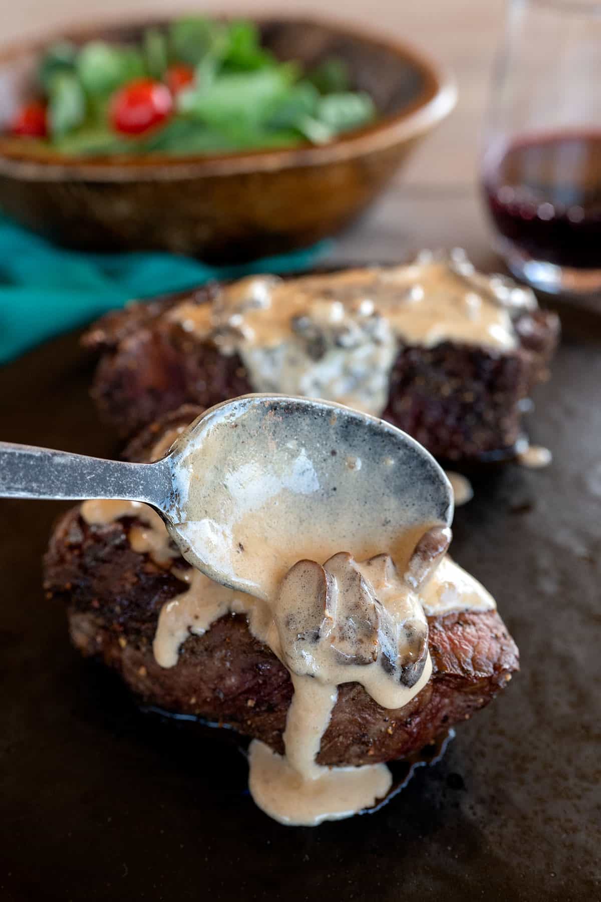 spooning mushroom sauce over grilled filet steaks.