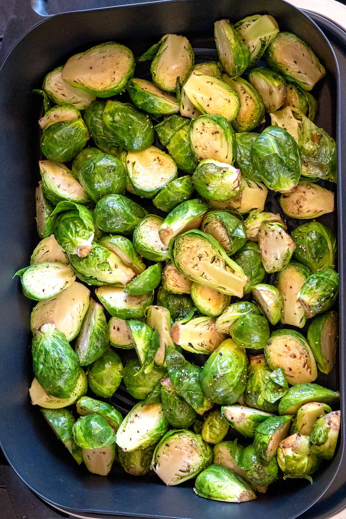 seasoned brussels sprouts in air crisper basket on grill.