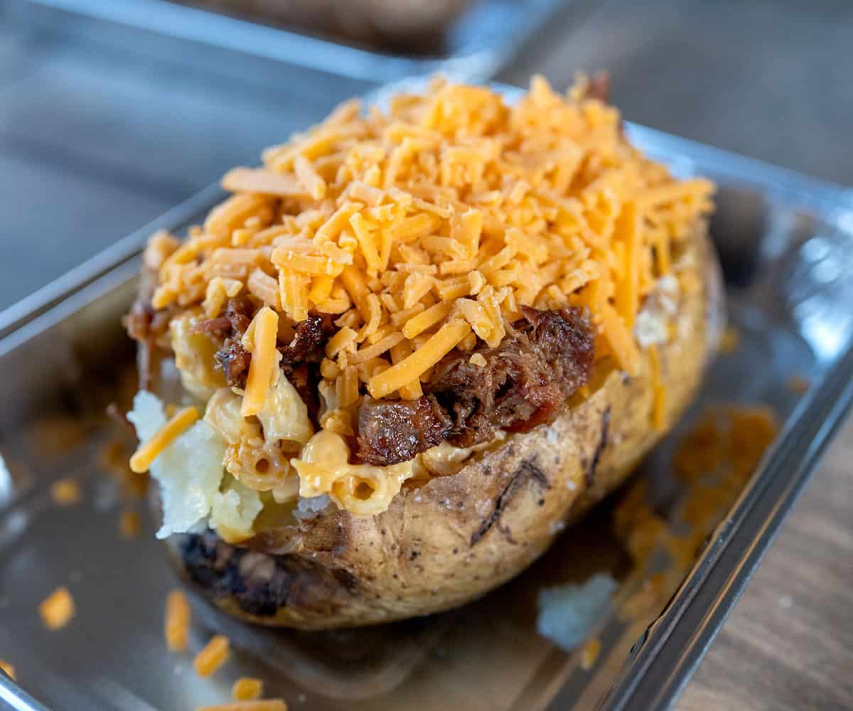 baked potato topped with macaroni, pulled meat and shredded cheese.