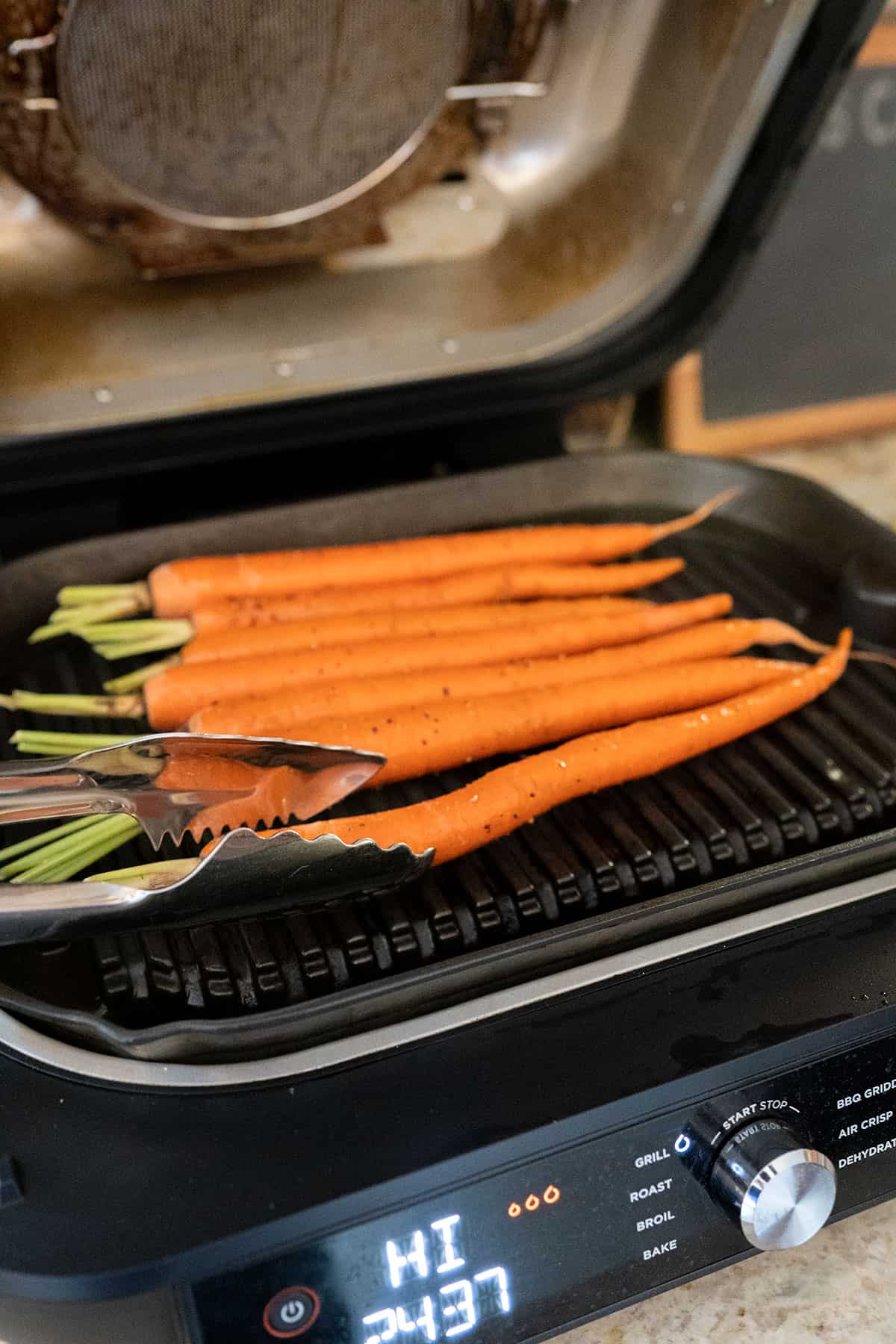 turning carrots on Ninja Grill with tongs.
