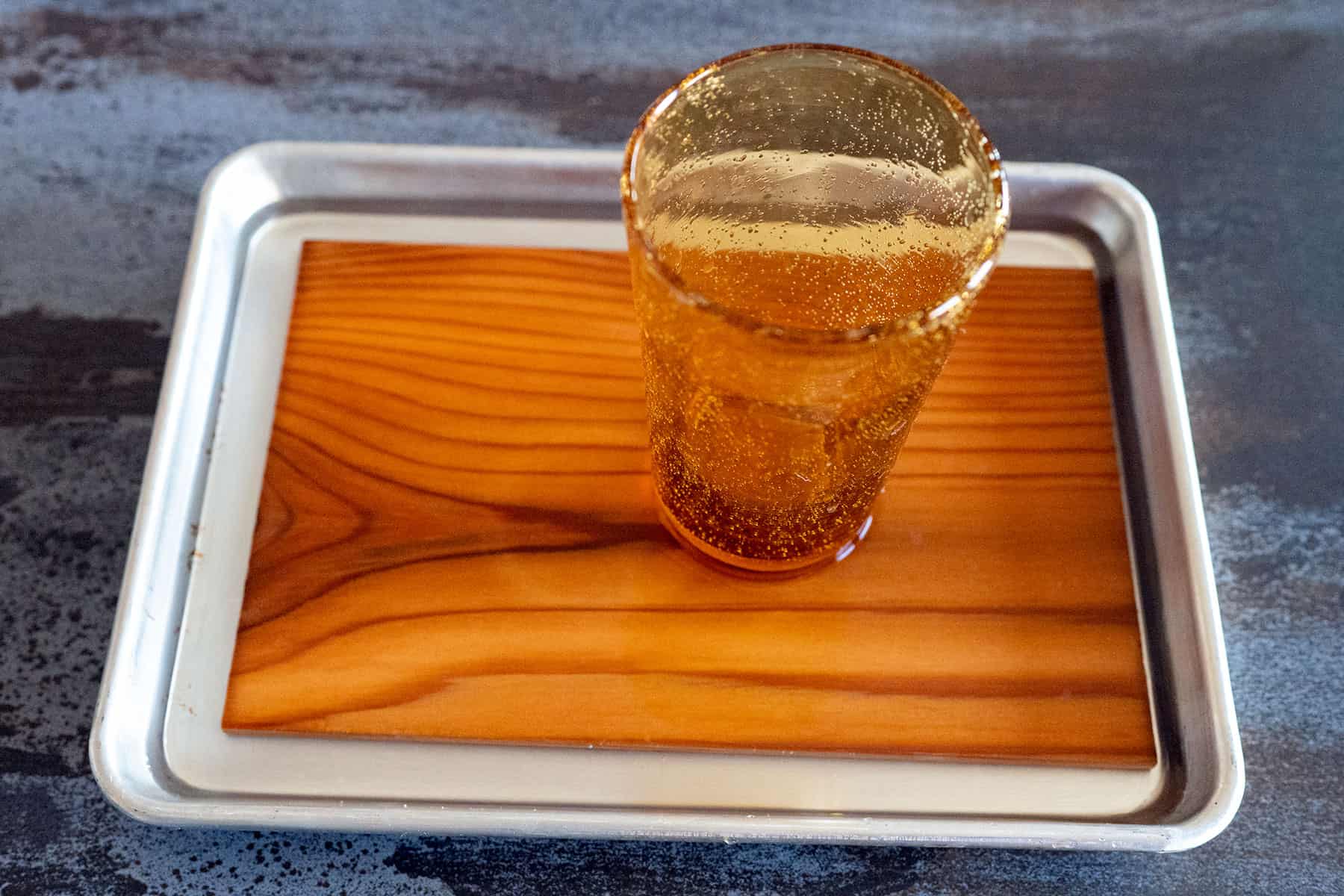 cedar plank in pan with water being held down by heavy glass.