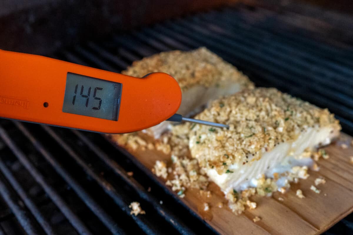 thermometer showing halibut at an internal temperature of 145F degrees.
