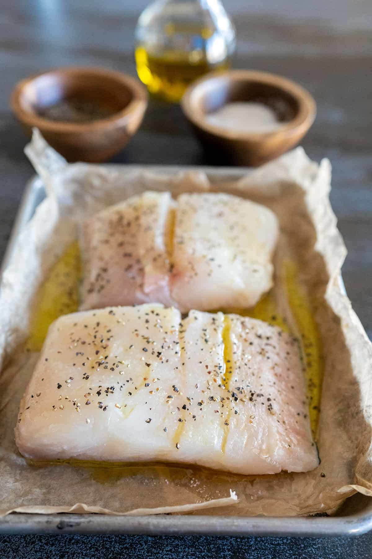 two halibut filets seasoned with oil, salt and pepper.