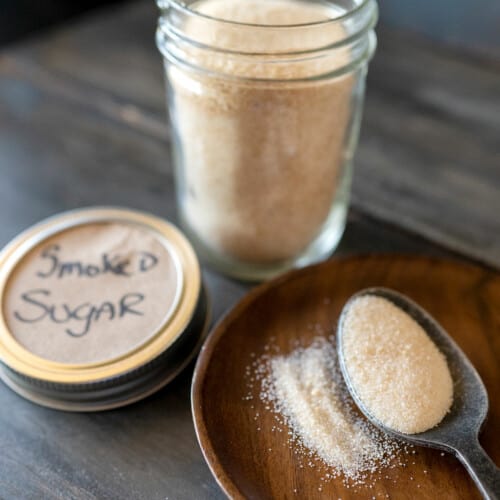 spoonful of smoked sugar next to a jar of smoked sugar.
