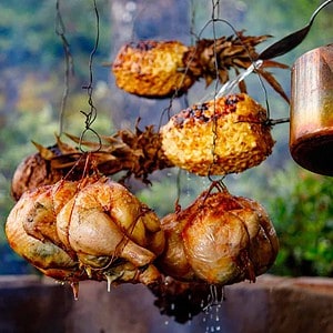 meat and pineapples hanging over fire.