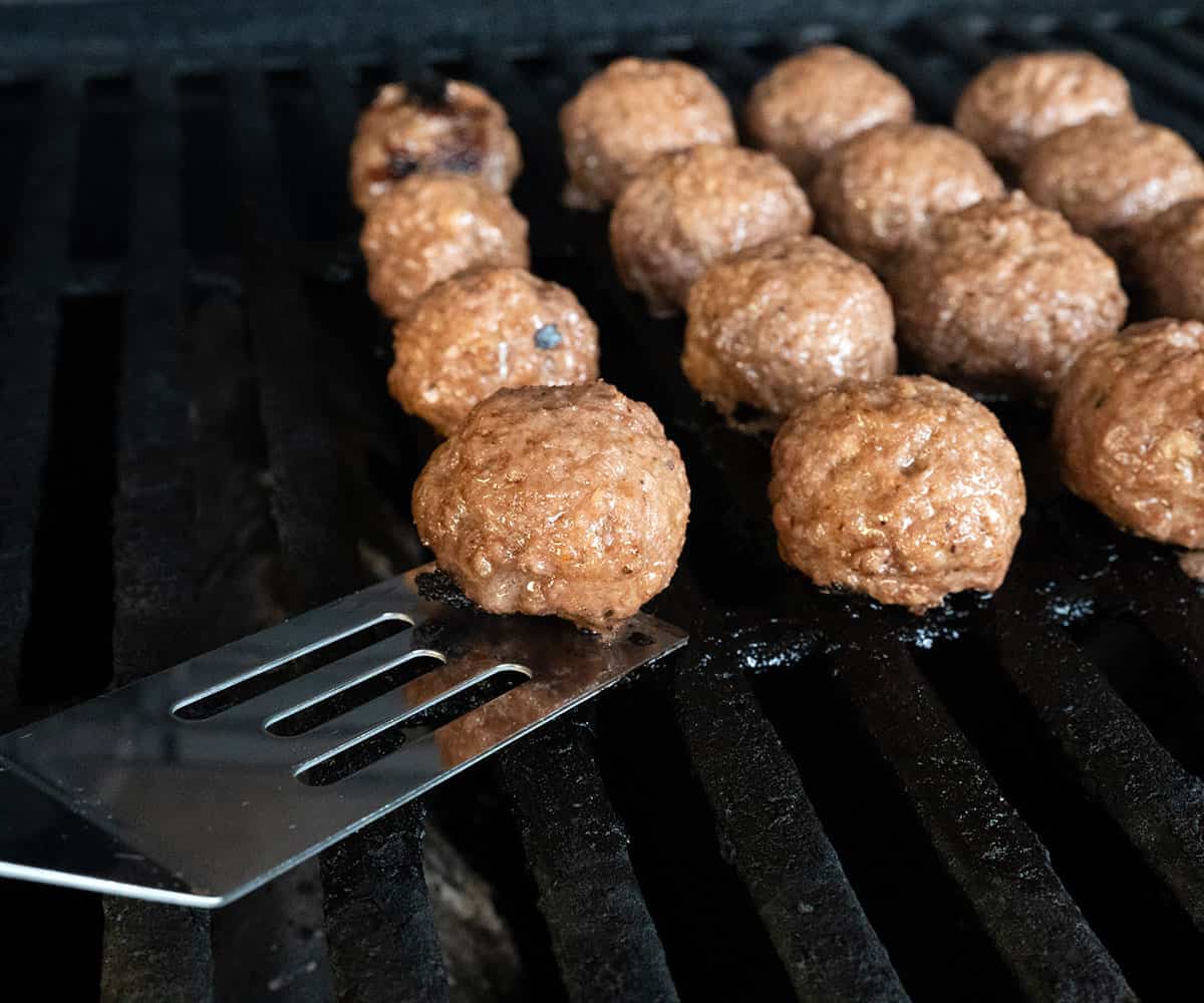 Releasing meatballs from grill with spatula.
