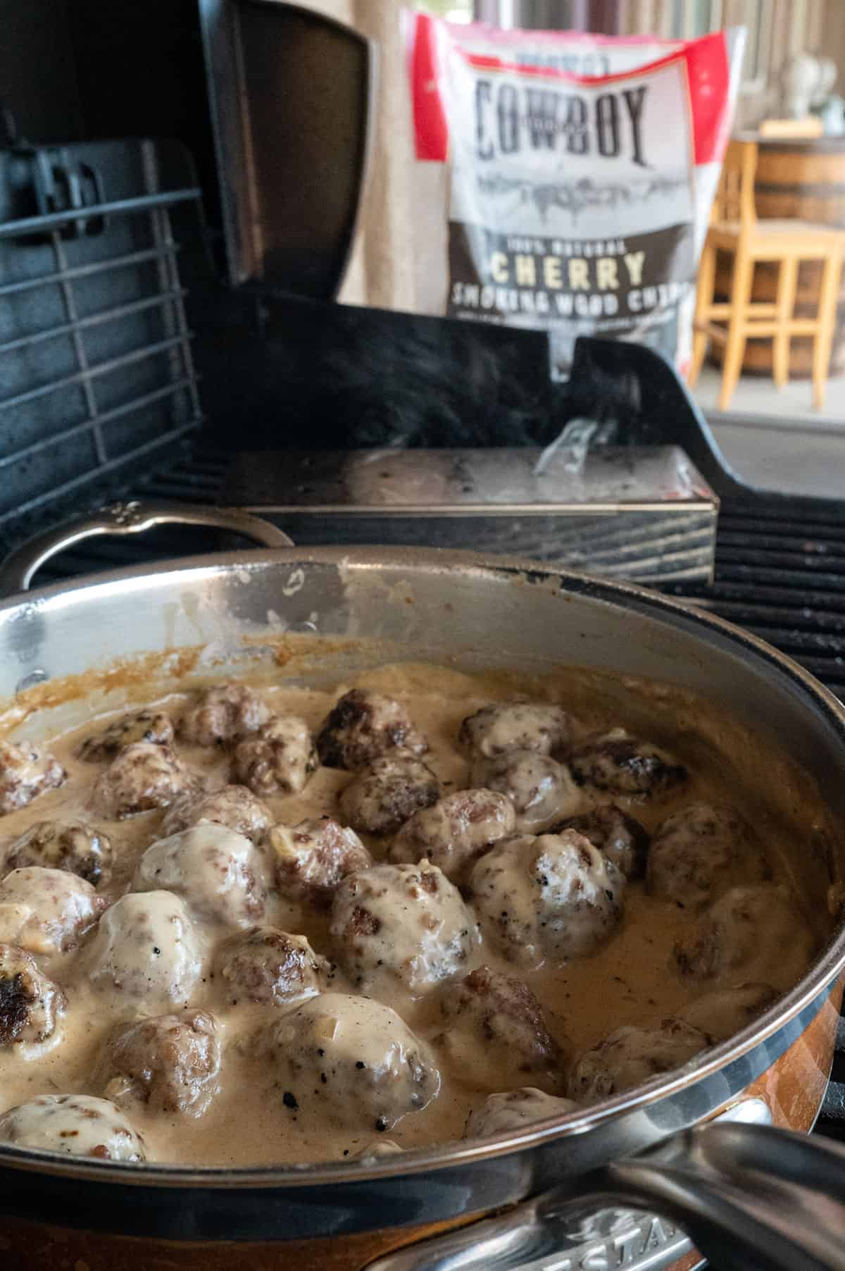 meatballs simmering in creamy sauce on grill.
