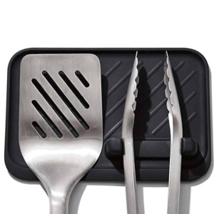 spatula and tongs resting on black pad.