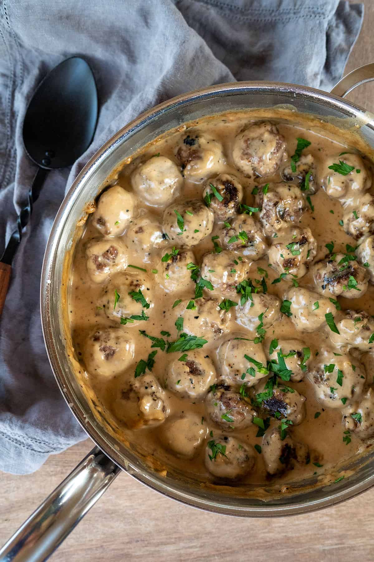 Swedish meatballs in sauce in skillet with parsley garnish.