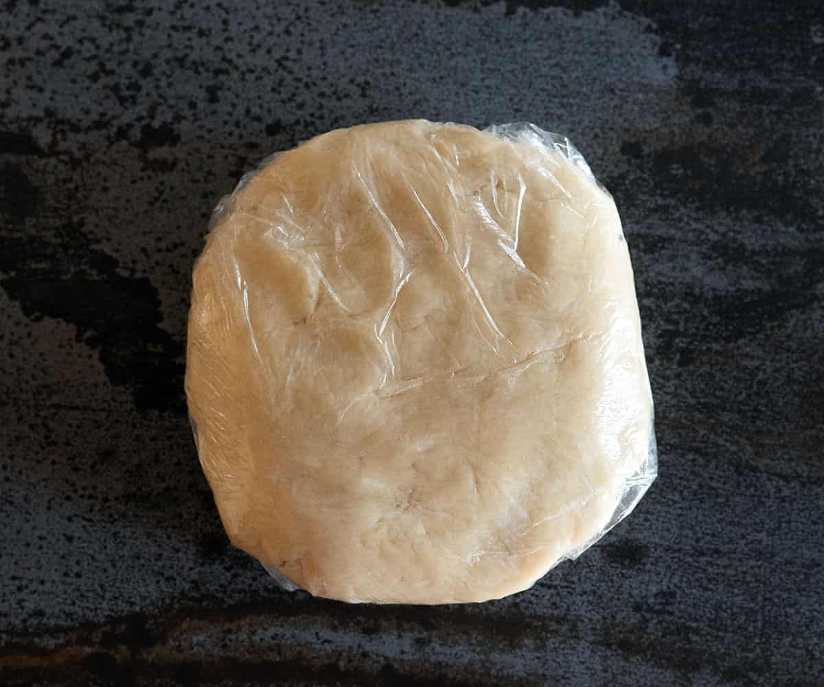 pie crust dough shaped into a disc and wrapped in plastic.
