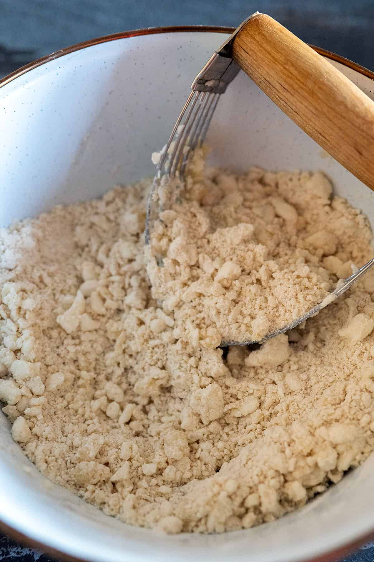 pastry blender mixing flour and fats to create pea-size balls.