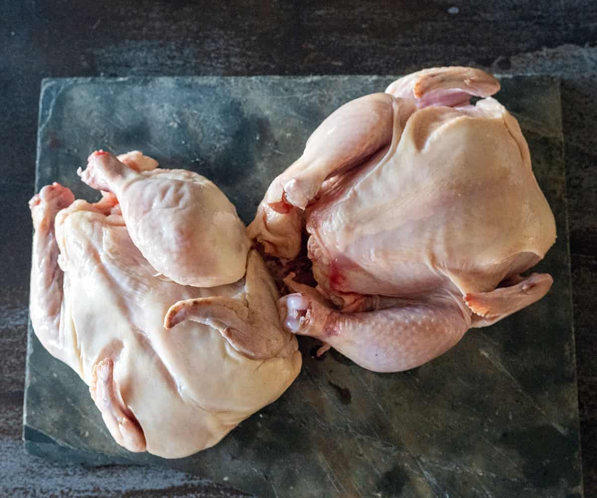 two raw cornish hens on slate.