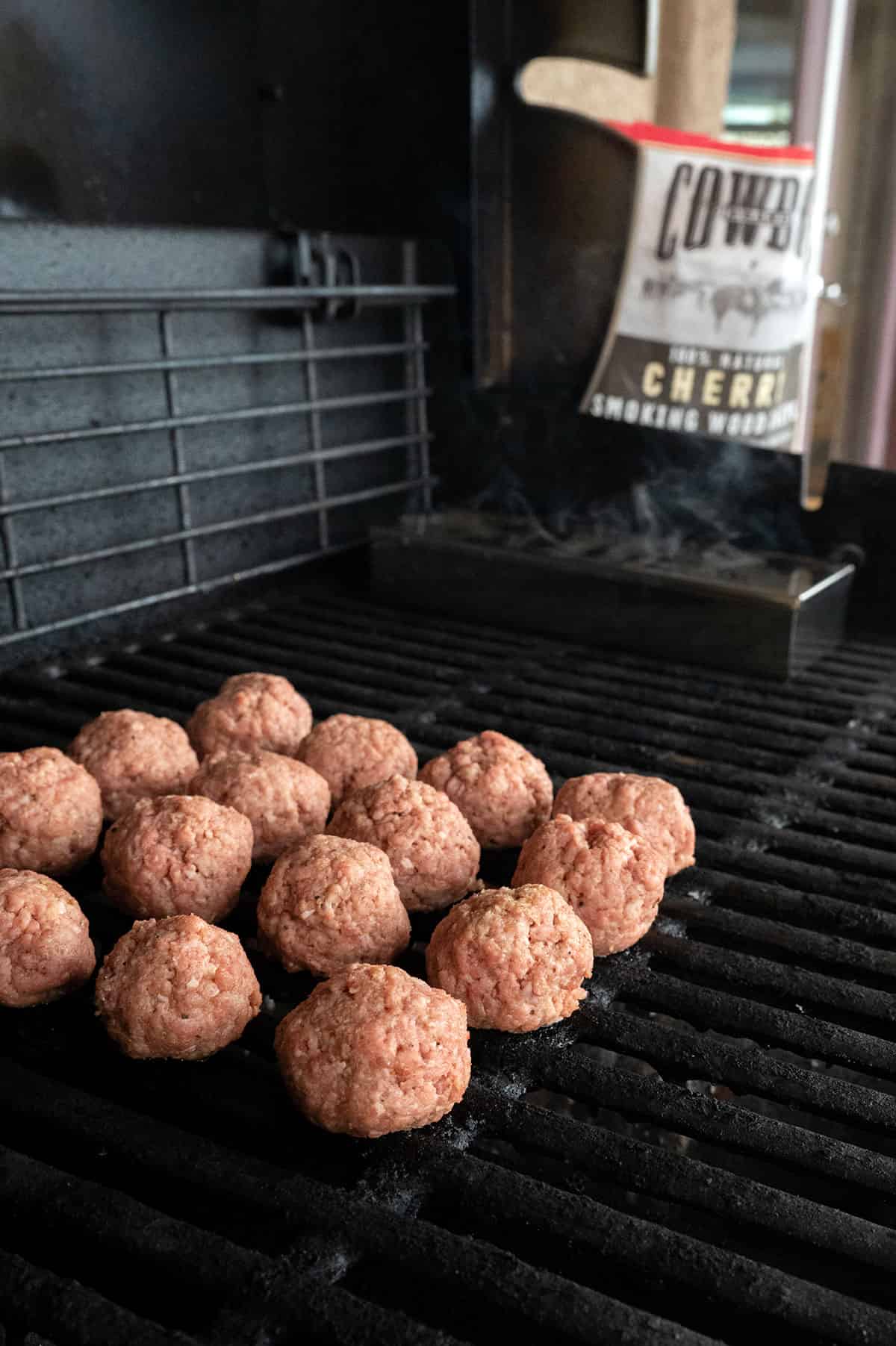 raw meatballs on grill by smoke box.