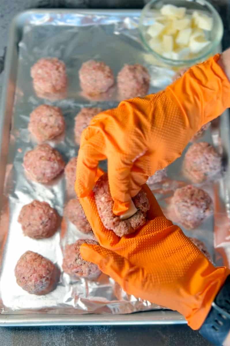 placing piece of cheese inside meatball.