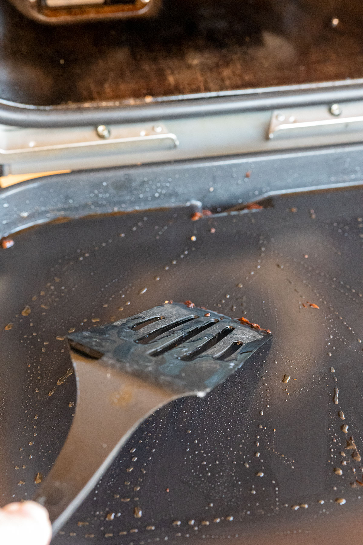 scraping griddle with rubber spatula.