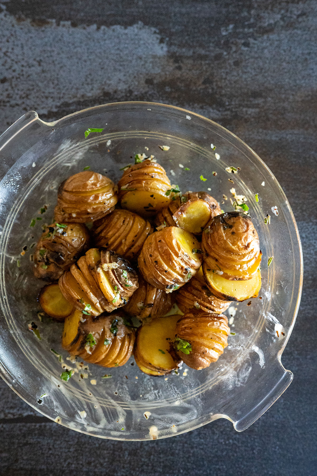 cooked mini hasselback potatoes in bowl with butter and herbs.