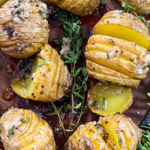 grilled mini hasselback potatoes on a platter with rosemary sprigs.