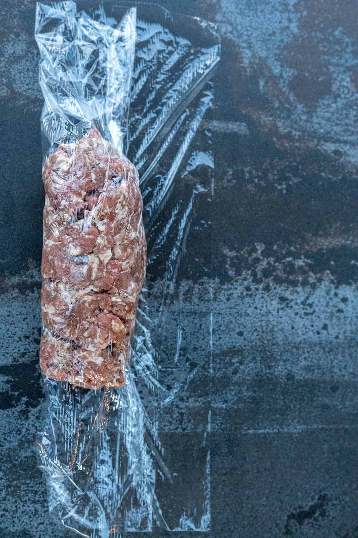 plastic wrap folded over log of breakfast sausage.