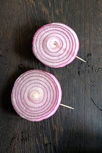 Sliced red onion rings with toothpicks inserted to hold rings together.