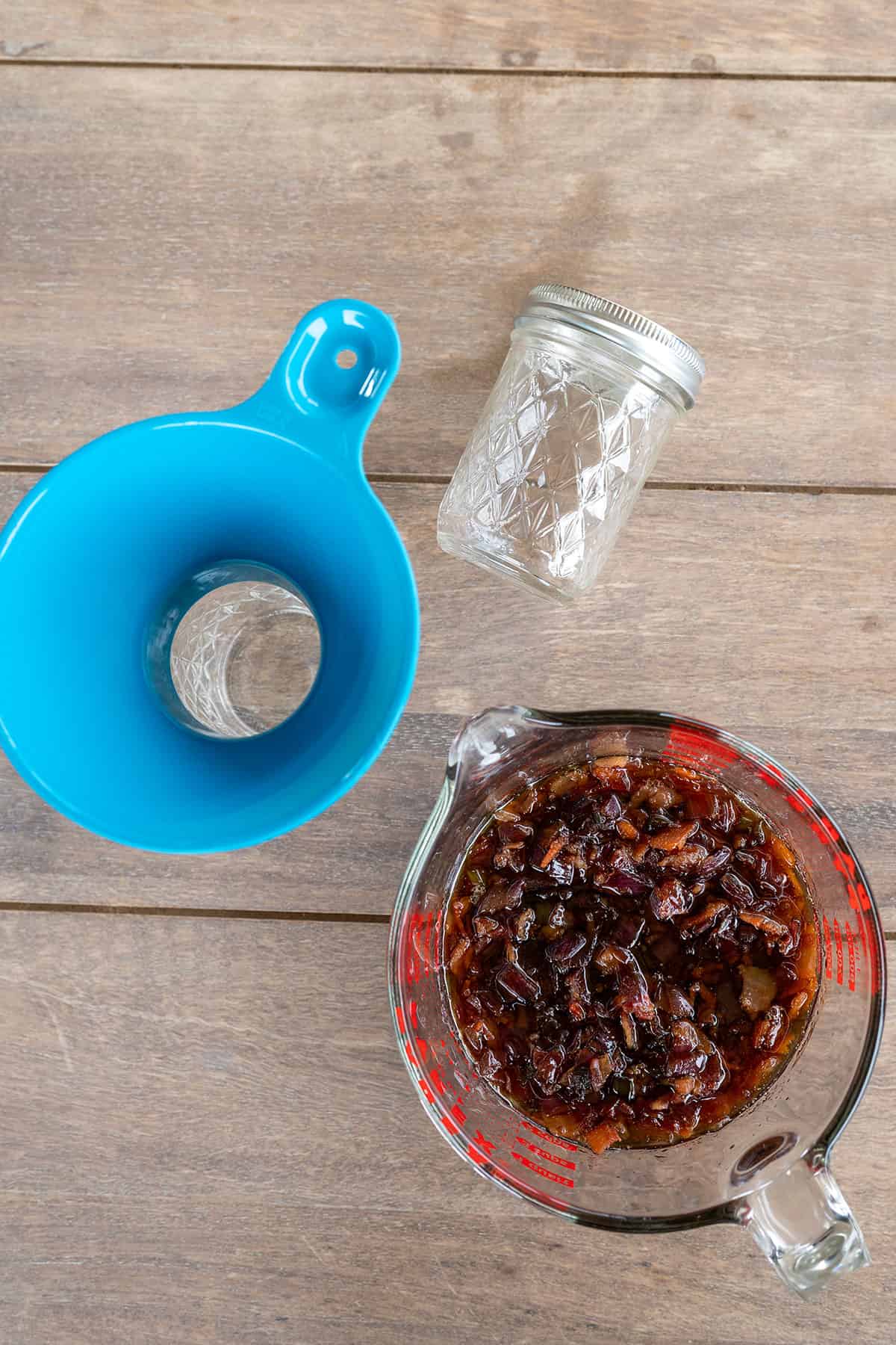 pitcher of bacon jam next to jar and jar funnel.