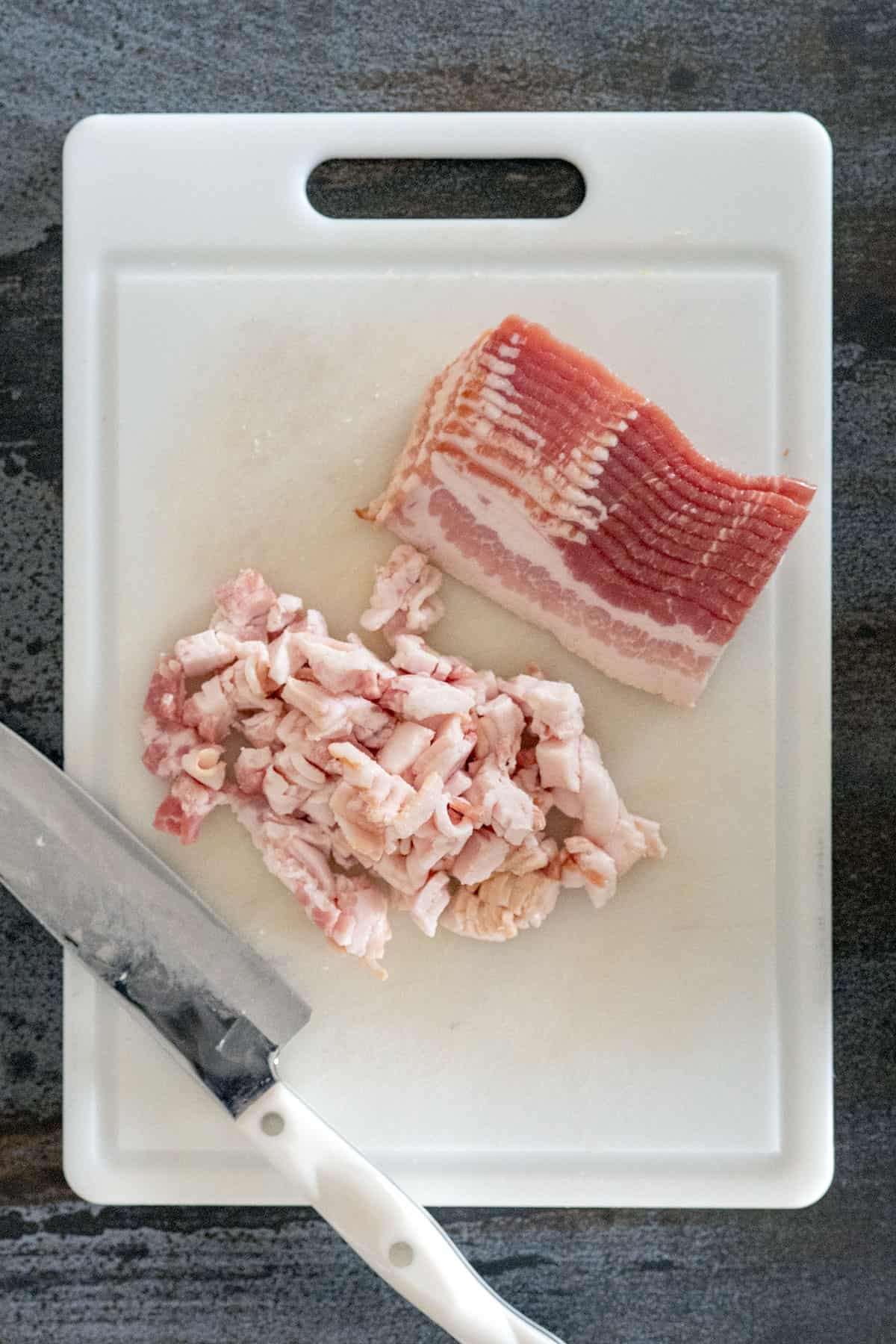 bacon on cutting board diced into smaller pieces.