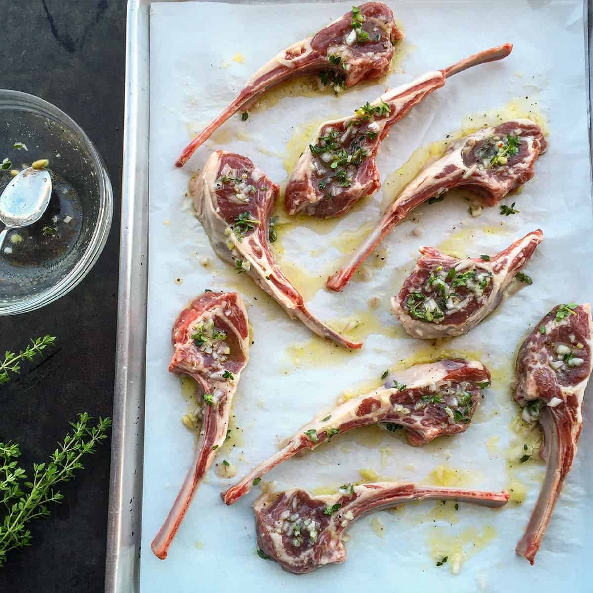 raw lamb chops with oil and herbs.