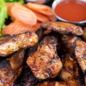platter of smoked chicken wings with carrots and hot sauce.
