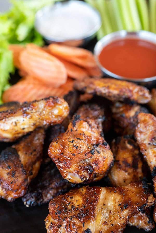 platter of smoked chicken wings with carrots and hot sauce.