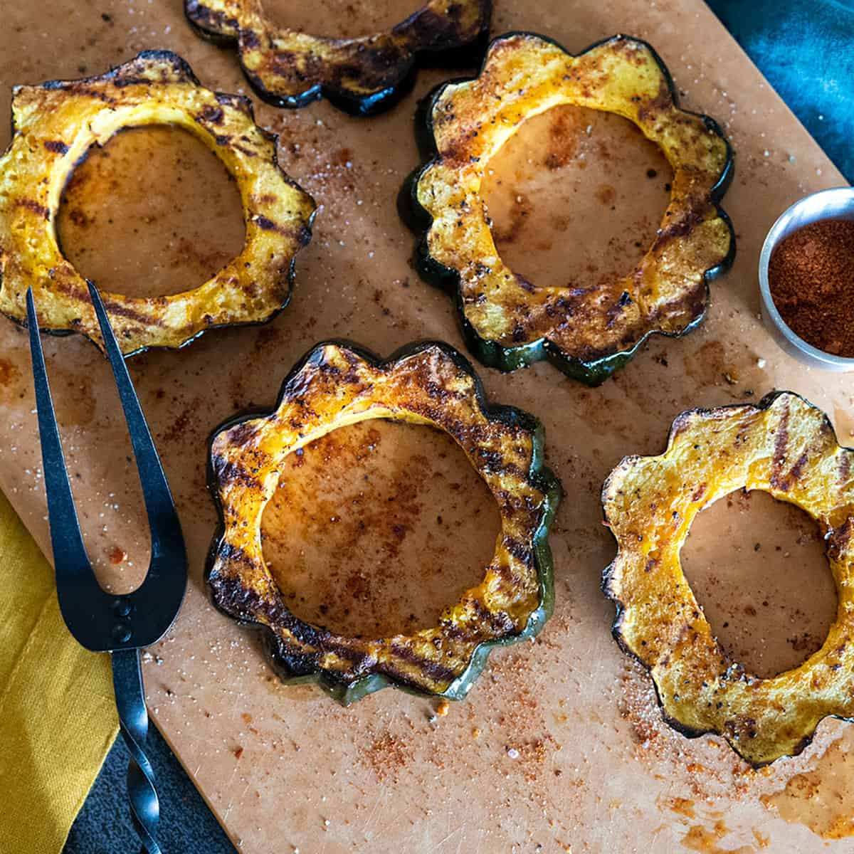 grilled acorn squash rings on platter by fork.