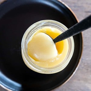 spoon scooping beef tallow out of jar.