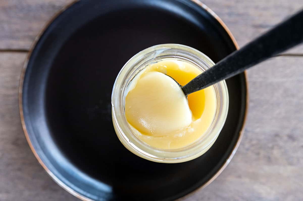 spoon scooping beef tallow out of jar.