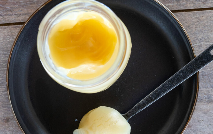 spoon of beef tallow on black plate next to jar of tallow.