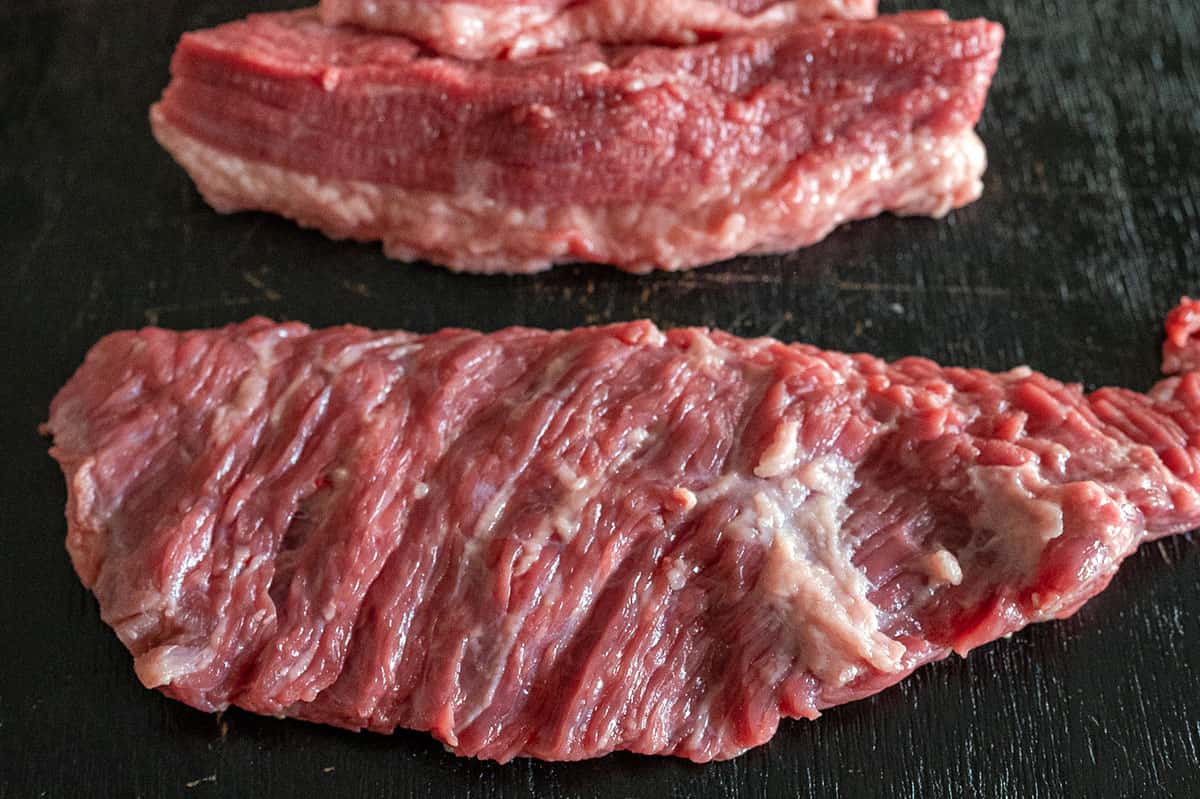 long flat slice of raw brisket point meat.