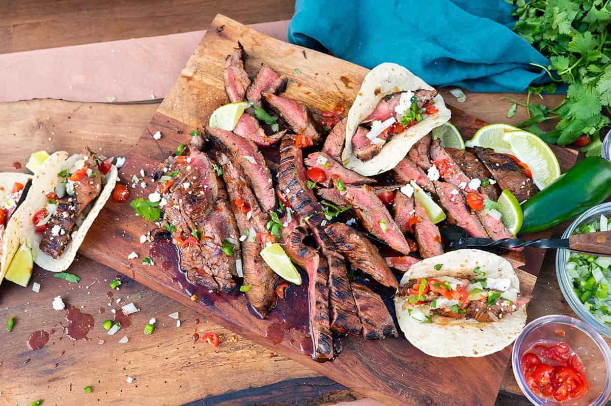 platter of sliced flank steak and tacos.