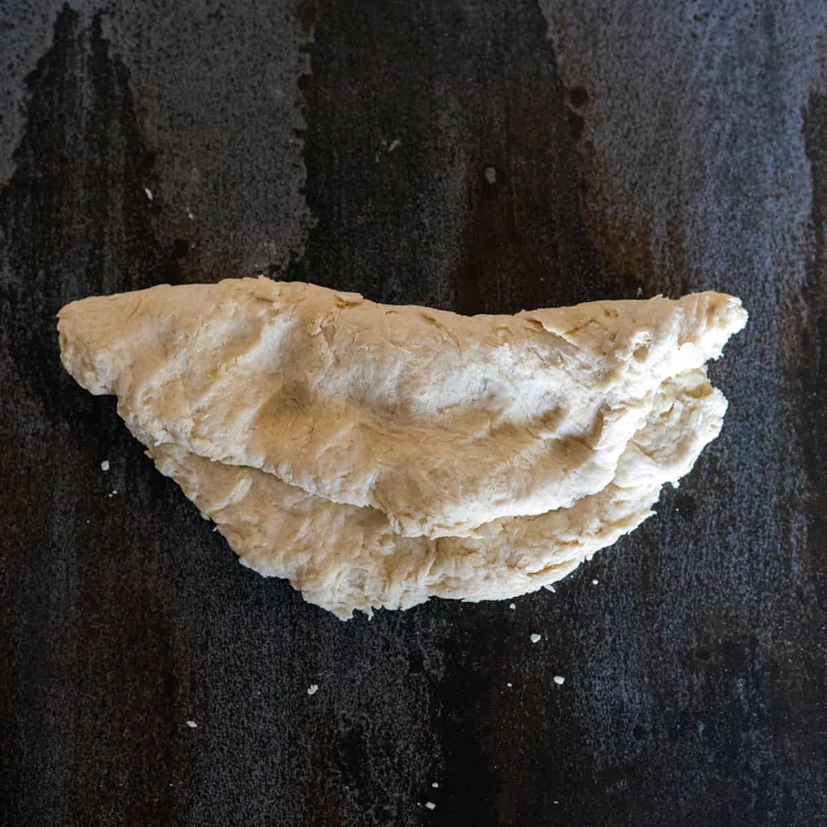 folding flattened tortilla dough in half.